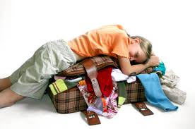 kid laying on suitcase full of clothes