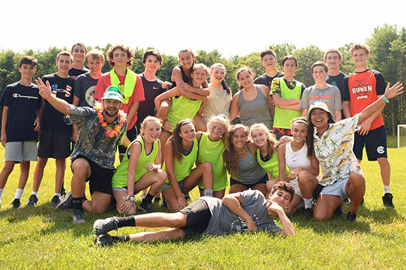 kids and counselors smiling on field at summer camp 