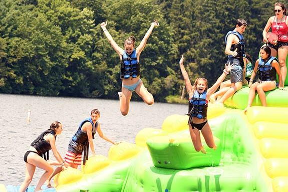 kids jumping on float in water at trout lake